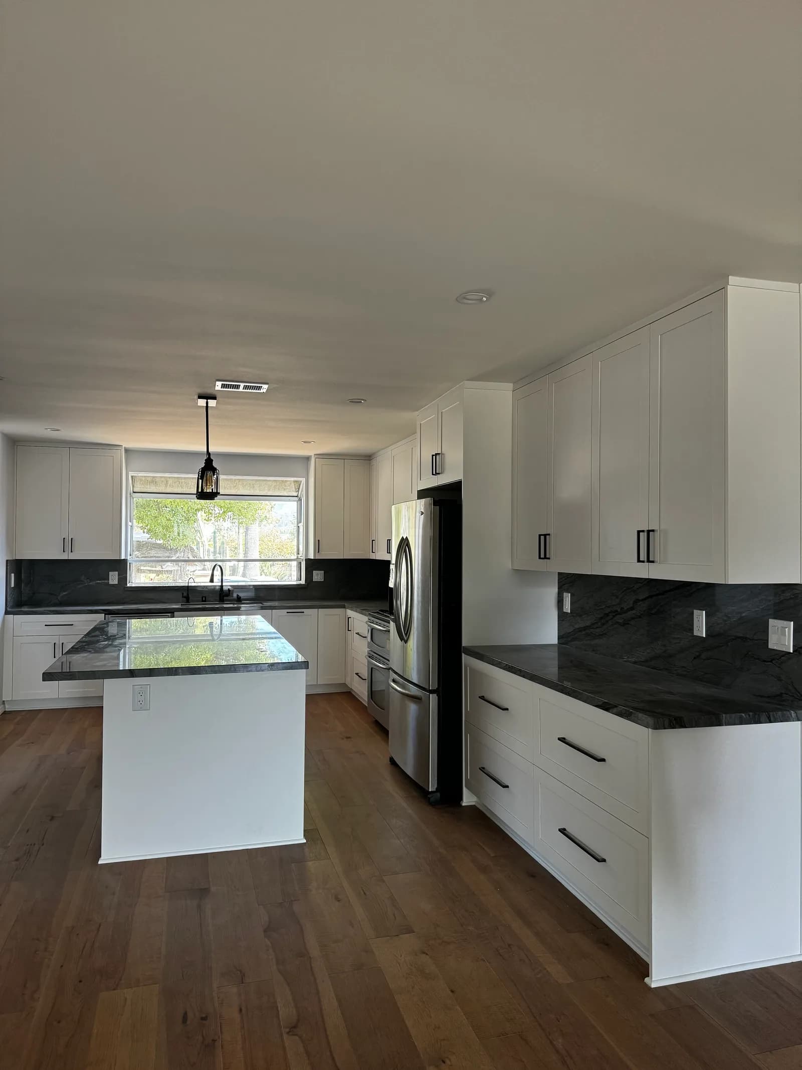 Custom kitchen remodel with waterfall quartz island, paint-grade cabinetry, and oak flooring in Ventura County, CA