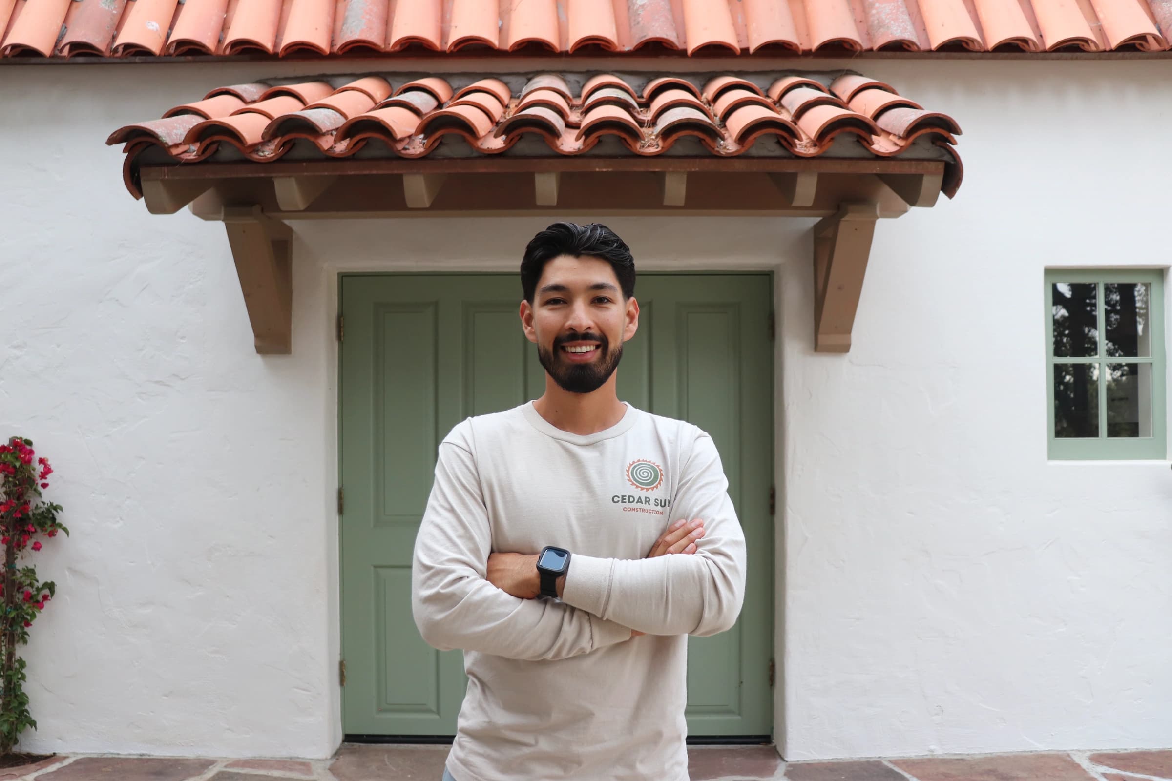 Isaak Hernandez, owner of Cedar Sun Construction, in a Cedar Sun long-sleeve tee outside a Spanish Revival home in Ventura County, CA
