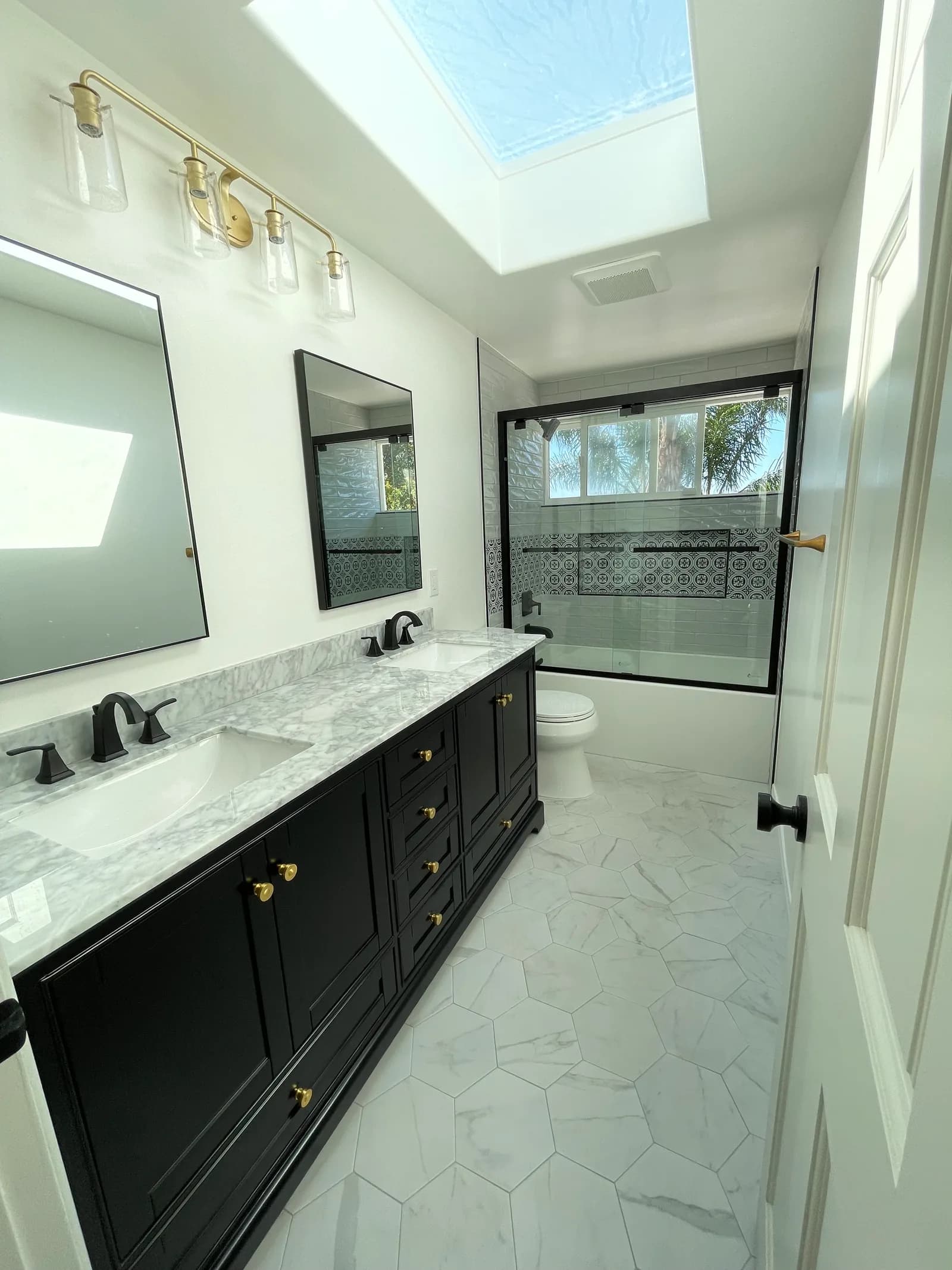 Master bathroom remodel with black double vanity, marble hex feature wall, and patterned tile shower in Camarillo, CA