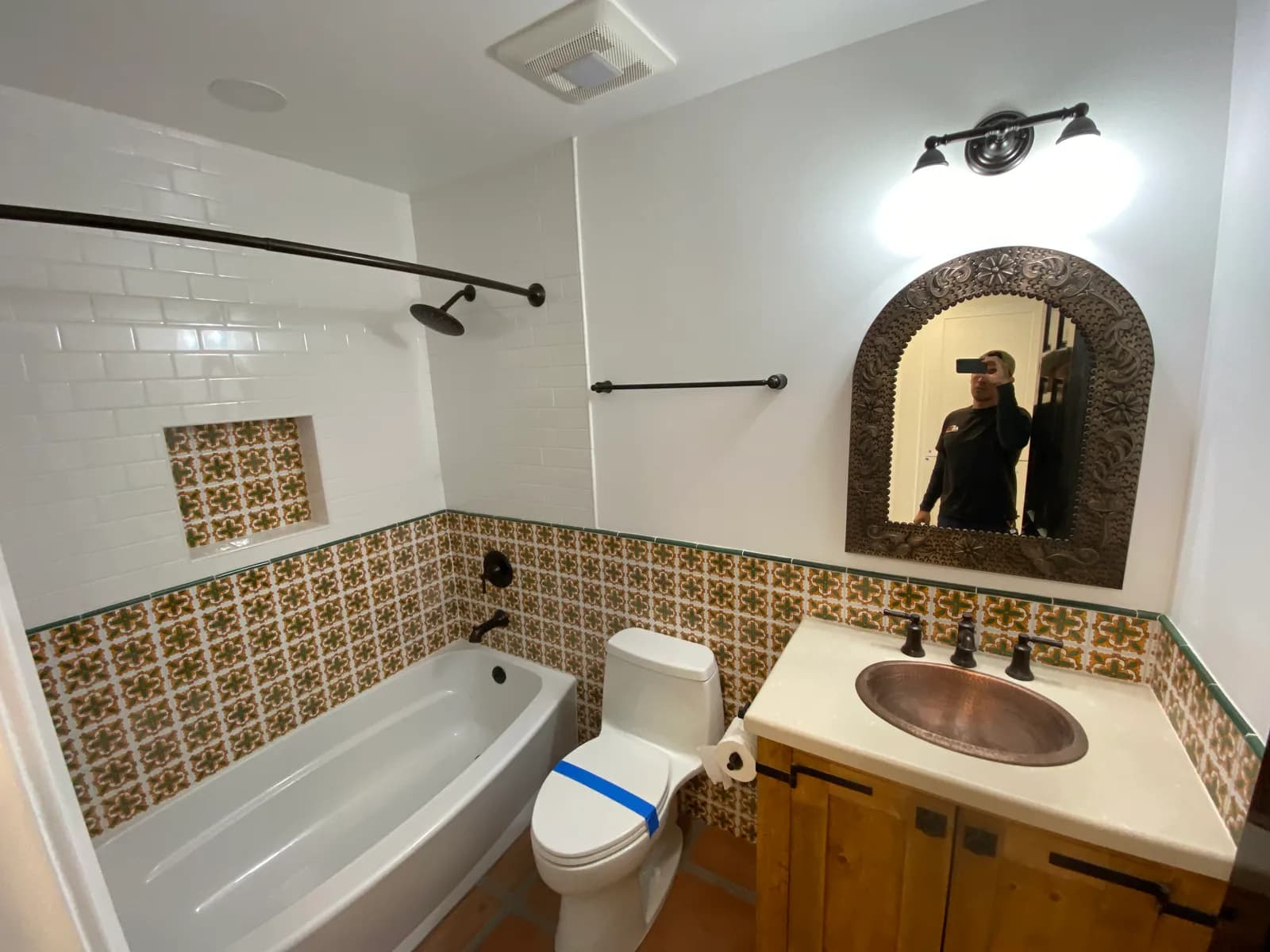 Spanish-style guest bathroom with hammered copper sink, Talavera tile wainscot, and subway tile shower surround in Santa Barbara, CA
